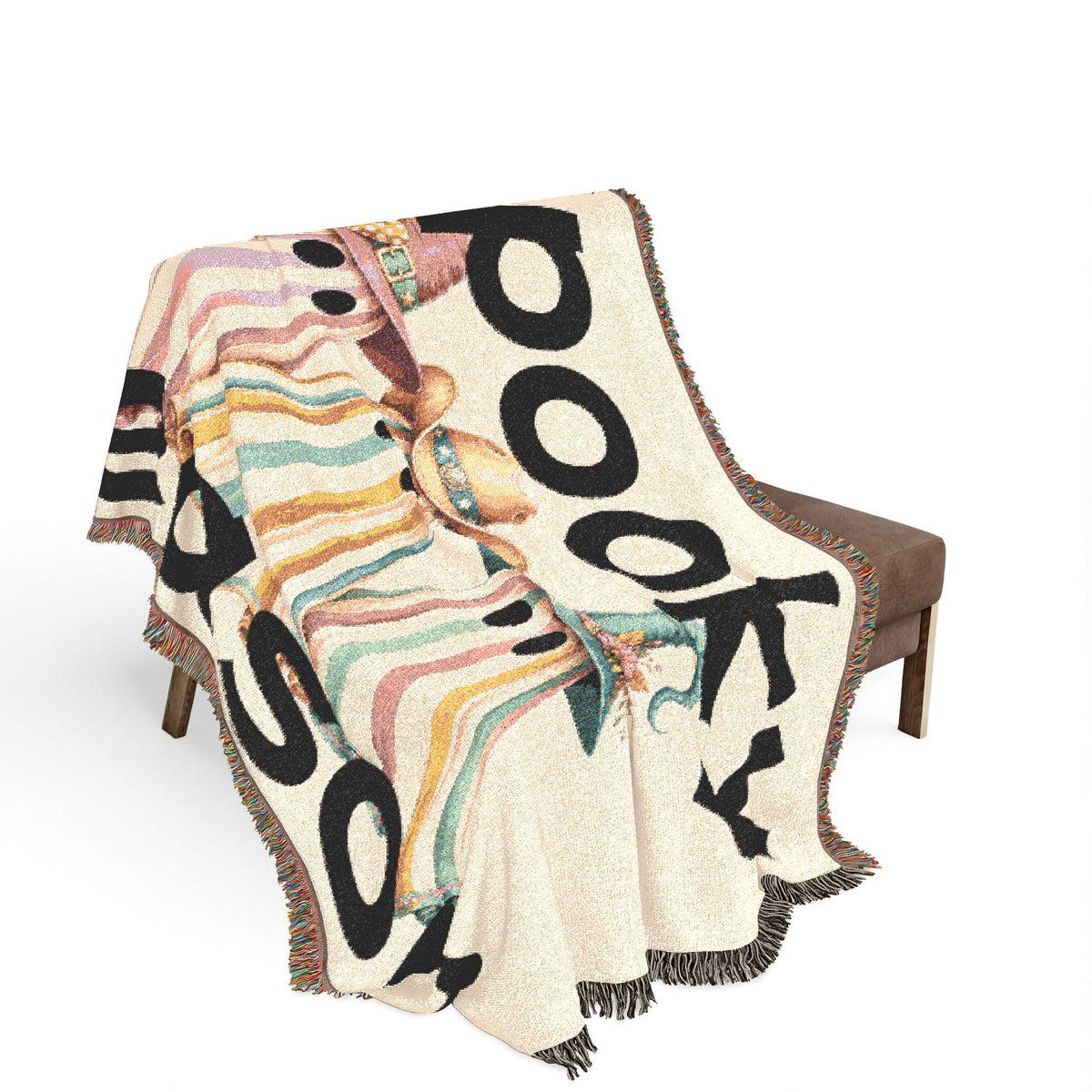 Woven cream throw blanket draped over a chair with pastel stripes and bold black BOO lettering plus playful Halloween motifs