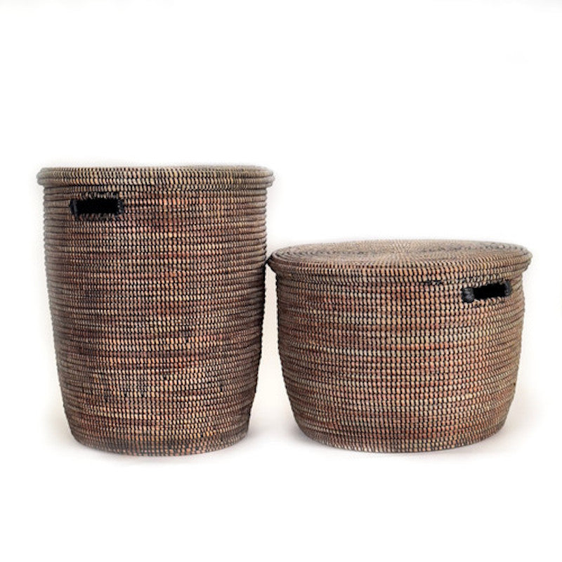 Two handwoven lidded storage baskets in dark black and brown tones with flat tops displayed together for practical minimalist home decor