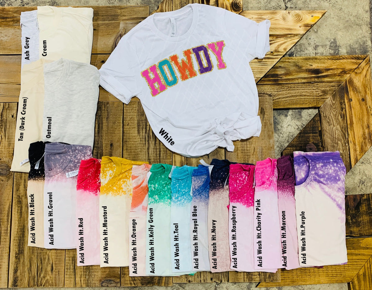 Women's white Howdy glitter graphic tee displayed with colorful fabric swatches showing available shades from DC Blonde Tees