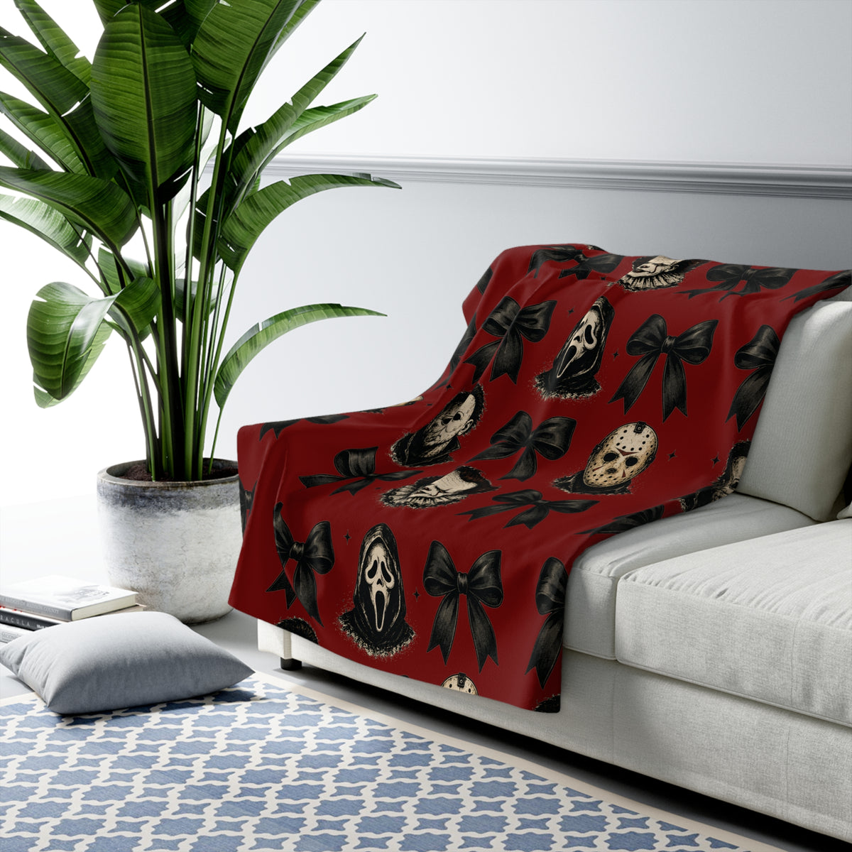 Vintage red sherpa blanket draped over a white sofa with spooky horror masks and black bows for cozy seasonal home decor and Halloween style