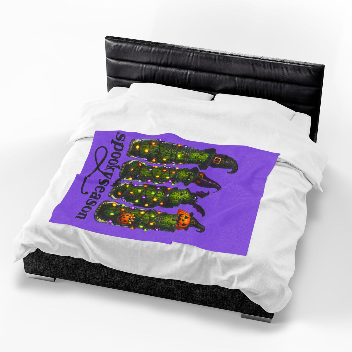 White bedspread featuring a purple Halloween graphic with four playful pickle characters wearing witch hats and pumpkin costumes