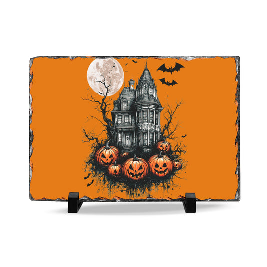 Halloween slate desk plaque with a haunted house under a full moon surrounded by bats and carved pumpkins on an orange background displayed on a stand