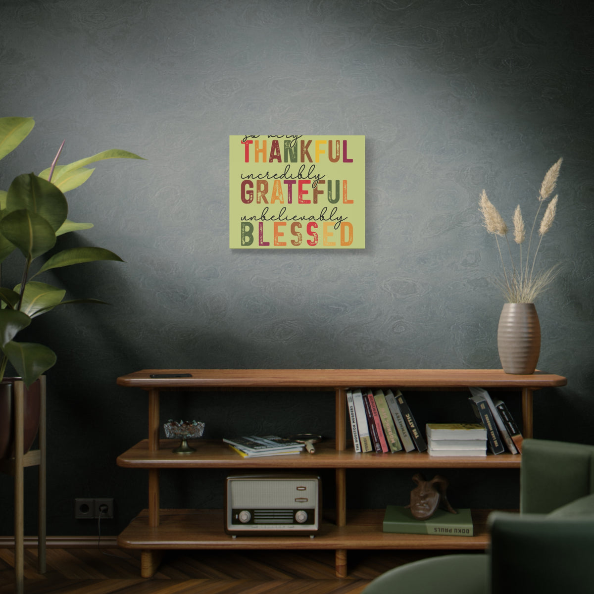 Autumn wall canvas featuring distressed lettering that reads Thankful Grateful Blessed above a wood bookshelf with books plants and a vase of dried grasses.