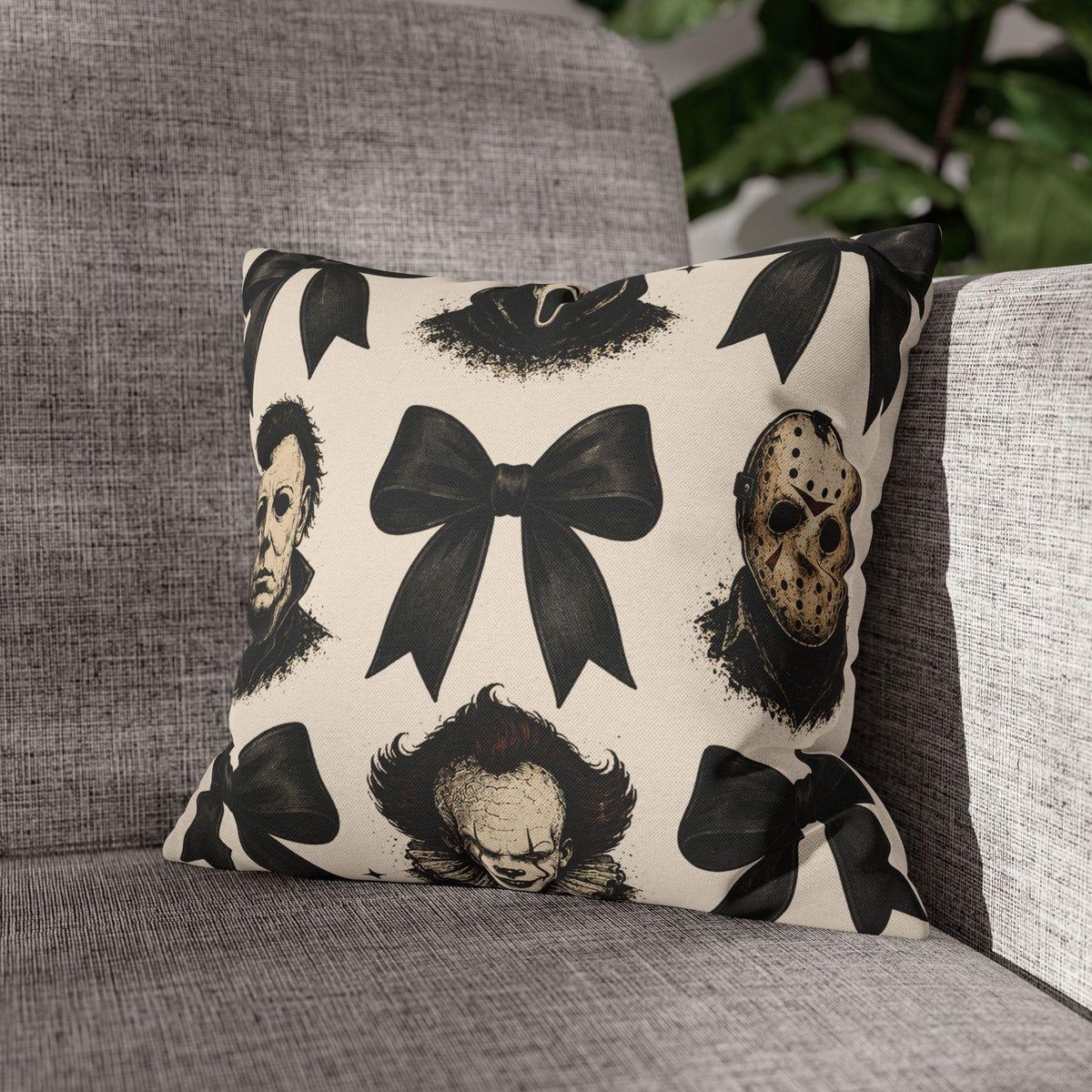 Cream square pillowcase with black bow motifs and vintage horror character masks displayed on a gray upholstered chair in a cozy home setting