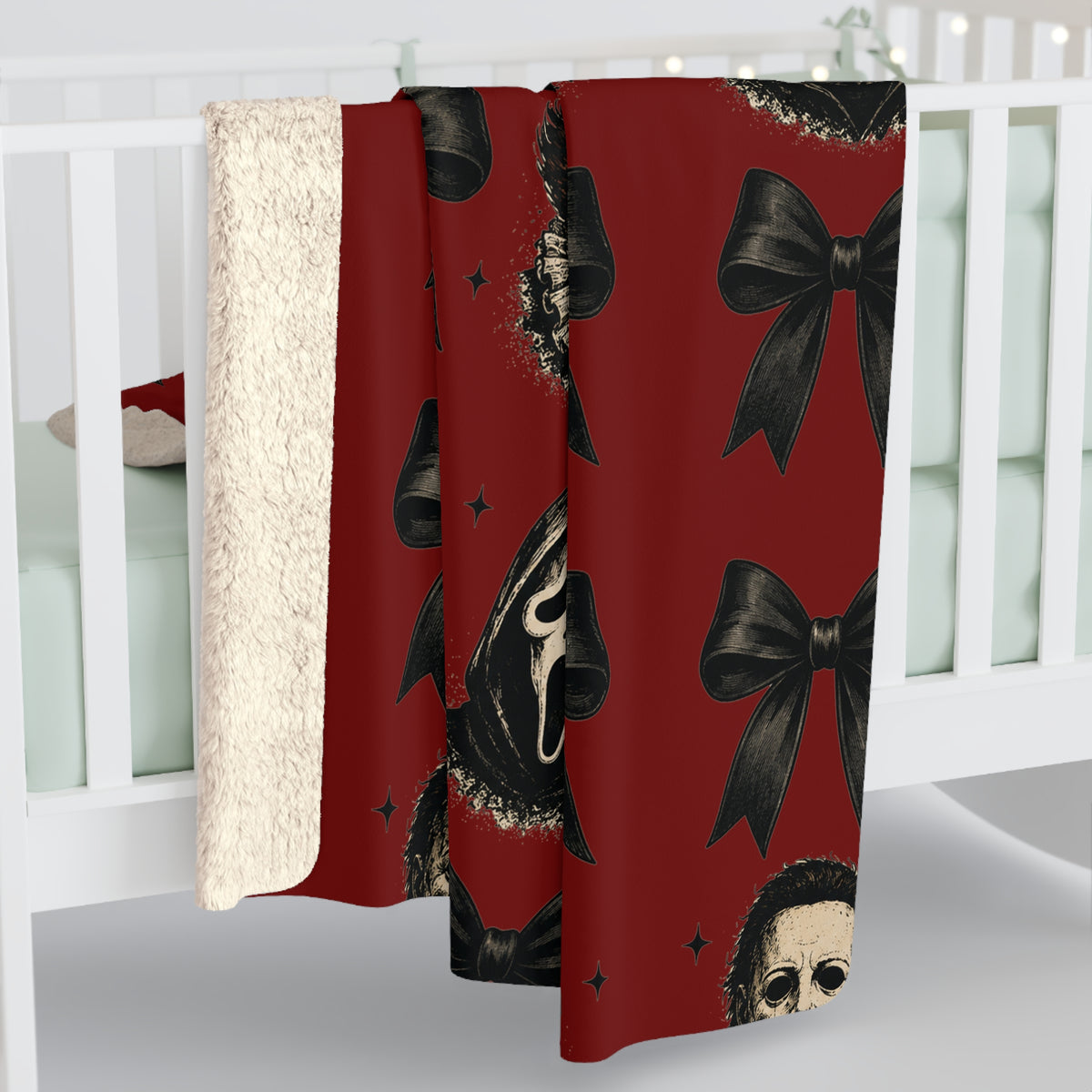 Red sherpa blanket draped over a white crib featuring black bows and eerie vintage horror masks with stars for seasonal home decor