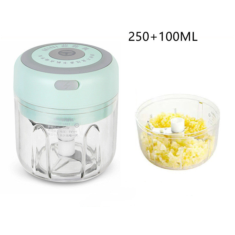 Mini electric garlic chopper with a transparent bowl and stainless steel blades shown filled with finely chopped garlic for quick food preparation