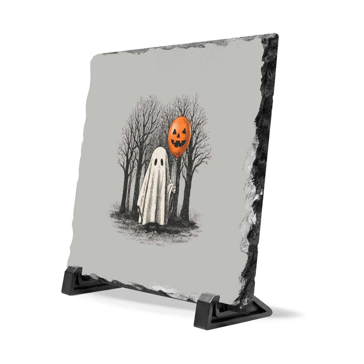 Hand cut gray slate desk plaque featuring a white ghost holding an orange pumpkin balloon among bare trees on a black stand