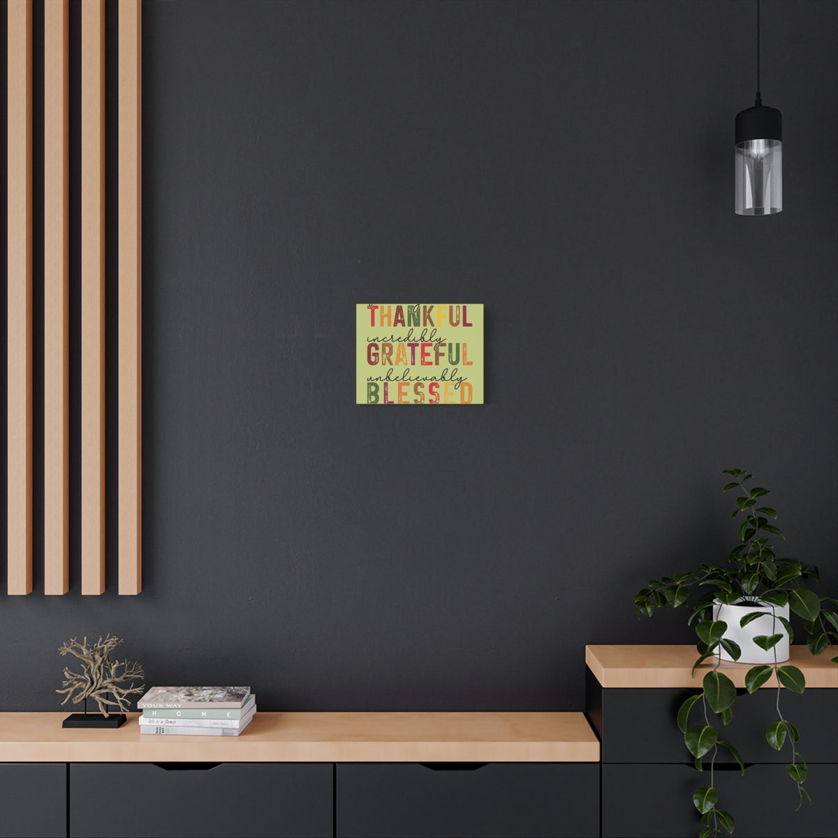 Autumn wall art canvas reading Thankful Grateful Blessed above a wood console in a modern dark room with plants and warm seasonal home decor