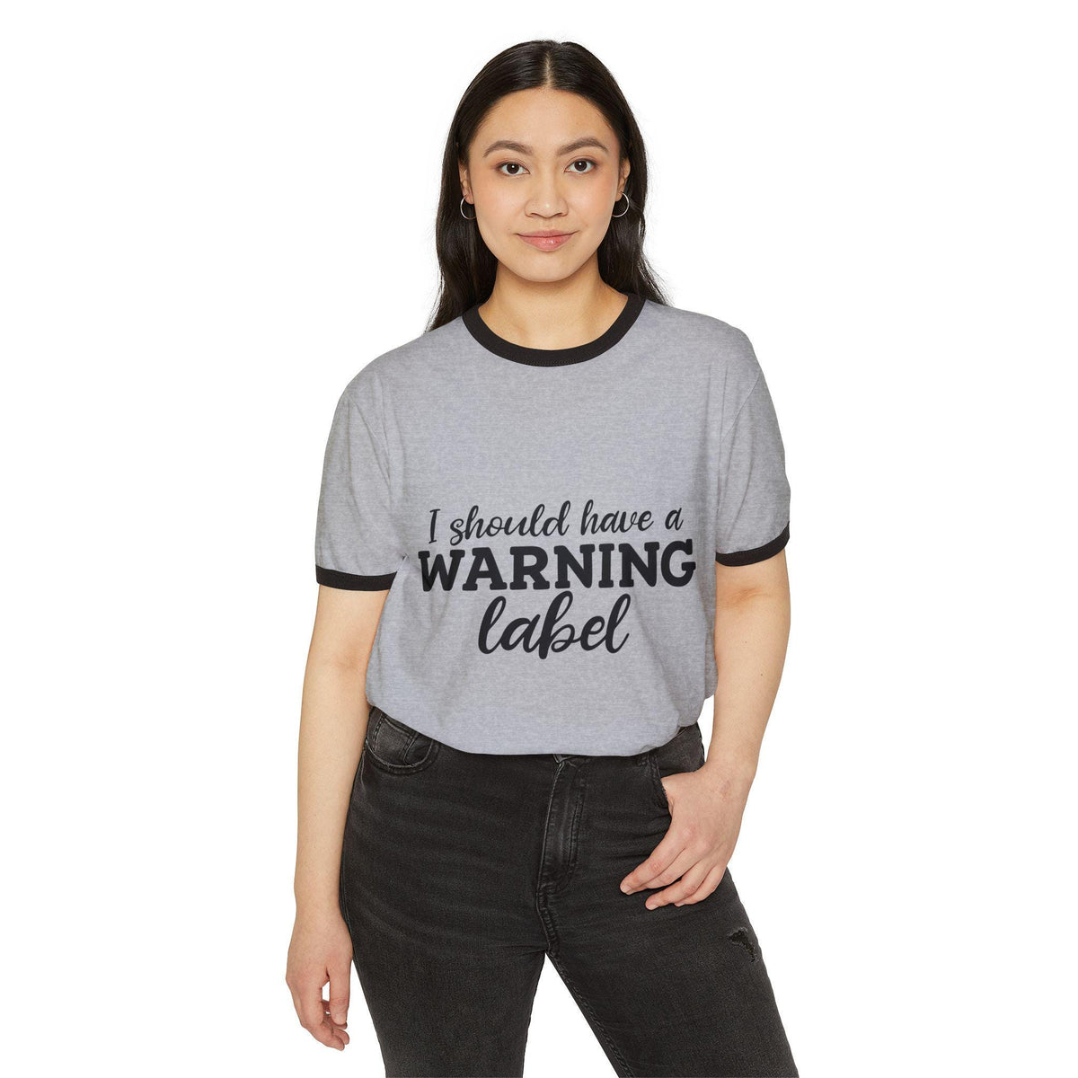 Woman modeling a gray ringer tee with black trim and the graphic message I Should Have a Warning Label paired with black jeans