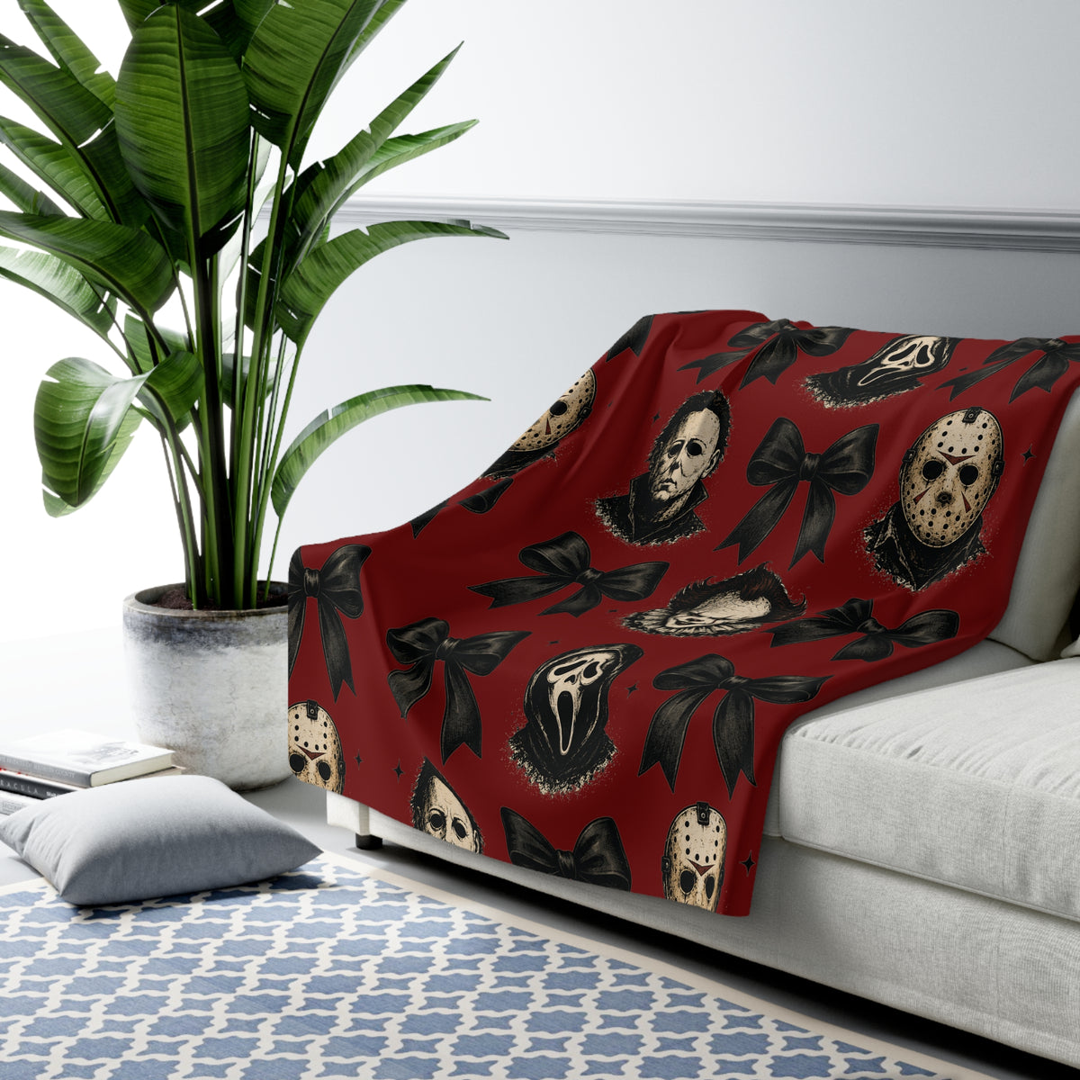 Red sherpa throw blanket with horror masks and black bows draped over a light sofa in a stylish living room from Printify Home and beyond Seasonal Favorites