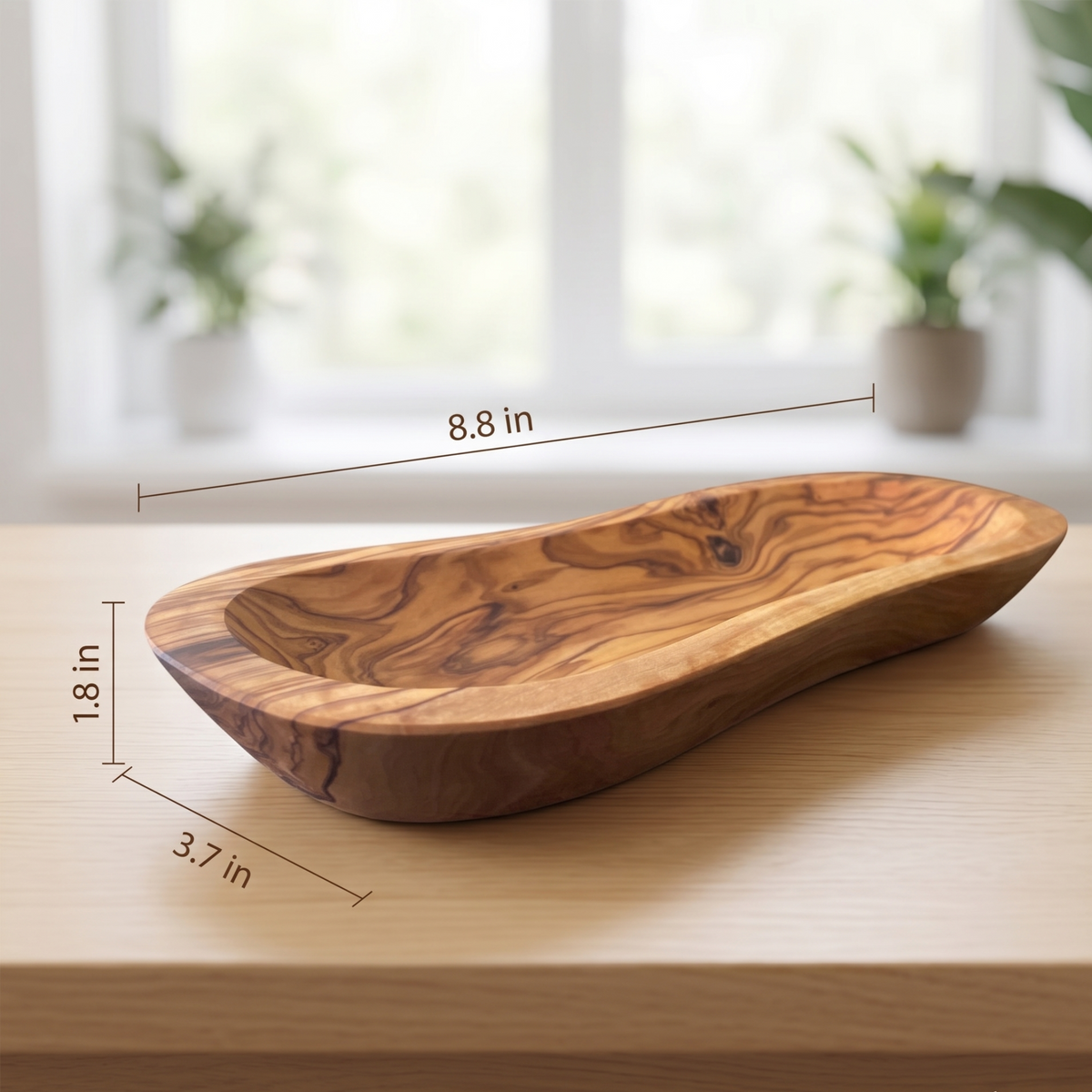 Elongated Mediterranean olive wood bowl with rich natural grain and a wavy shape displayed on a light wood table. DC-Choixe home decor from Home and beyond