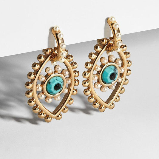 Gold plated eye motif earrings with pearl accents turquoise centers and textured bead details from Drizzle and Tizzle Jewelry