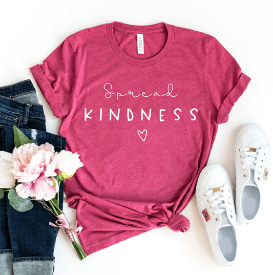 Pink graphic tee with Spread Kindness lettering heart detail blue jeans white sneakers and a bouquet of flowers styled for a women's fashion look