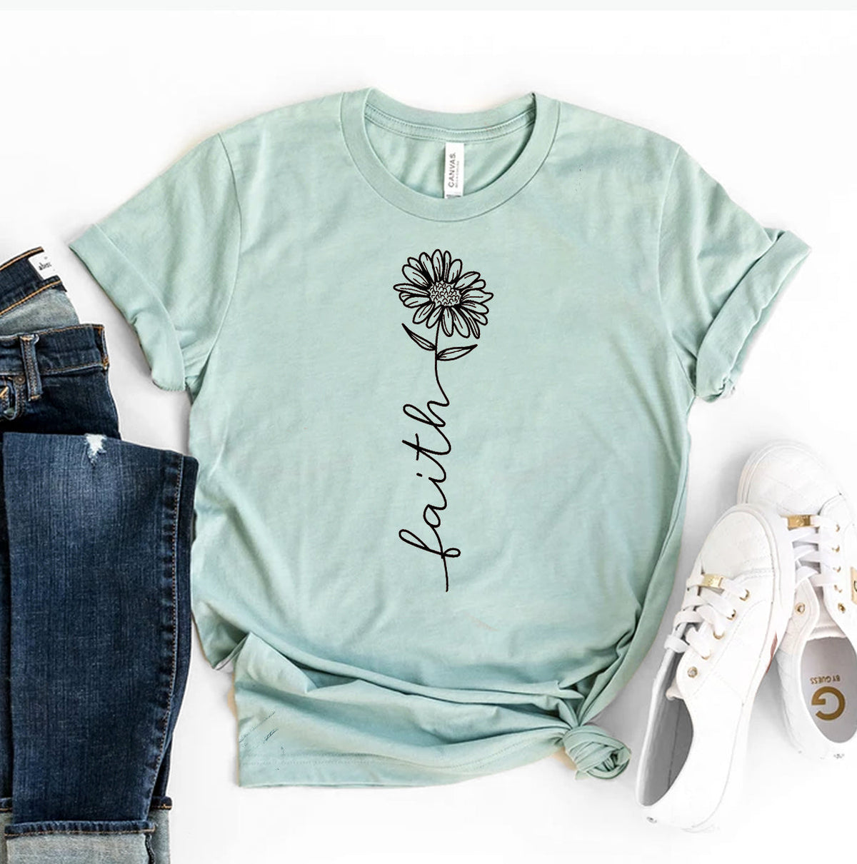 Mint green womens graphic tee with floral faith lettering styled with dark denim jeans and white sneakers for a casual outfit look
