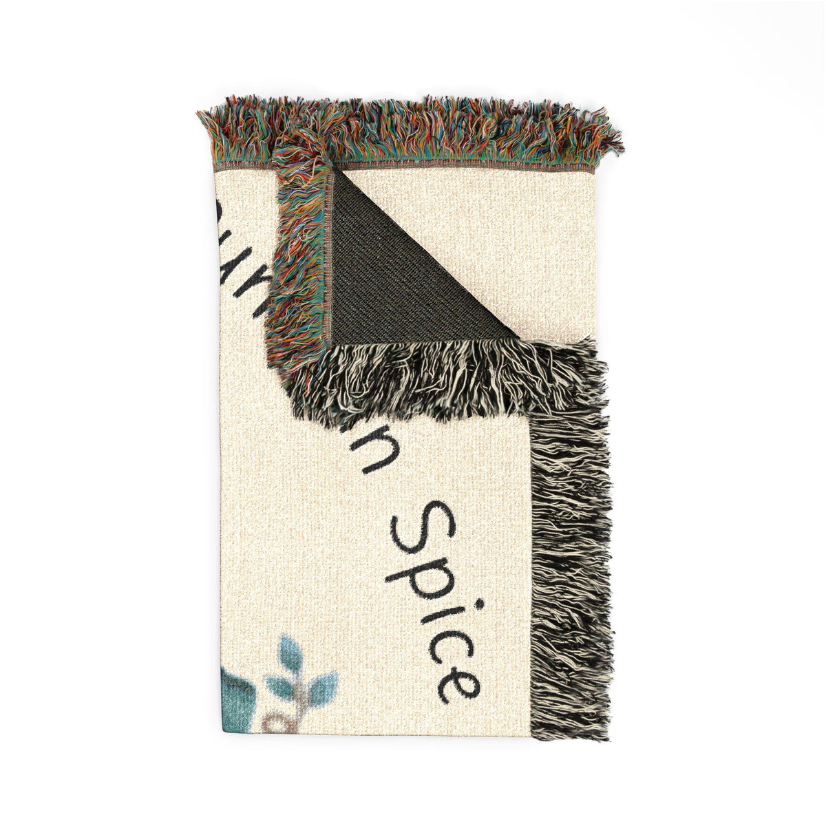 Folded woven autumn throw blanket with fringed edges cream background black spice lettering and a small blue botanical accent