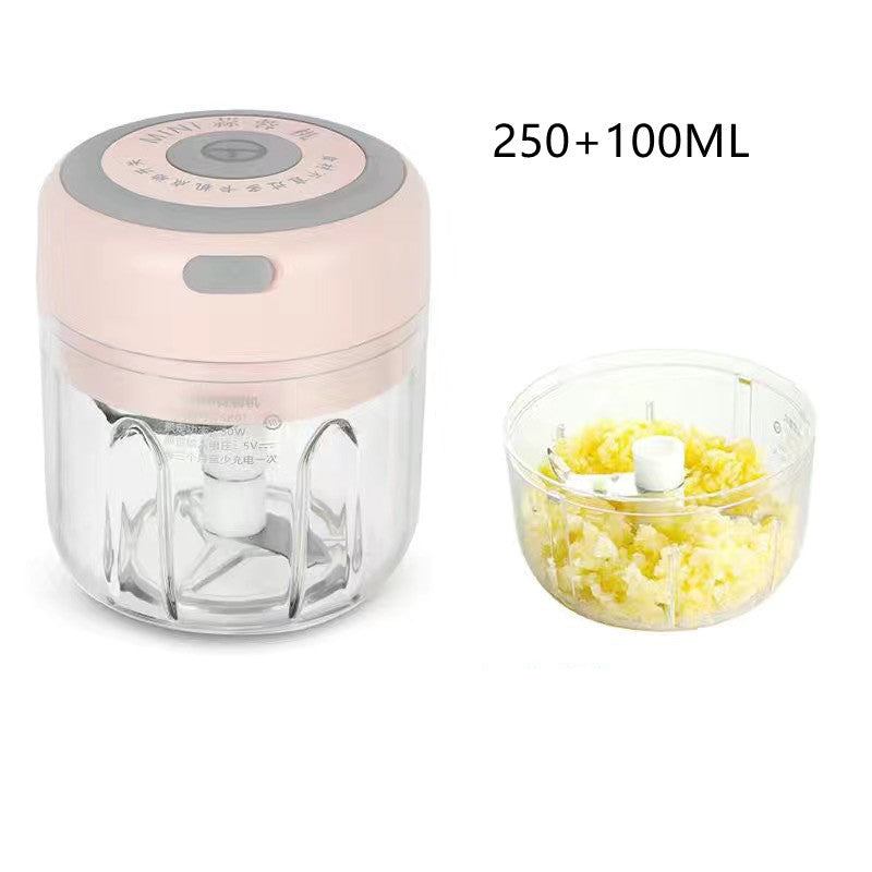 Mini pink electric garlic chopper with a clear bowl, stainless steel blade, and finely chopped garlic ready for cooking prep
