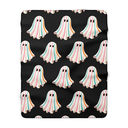Black sherpa throw blanket featuring a repeating pattern of pastel ghosts with pink blue and orange stripes for playful seasonal home decor