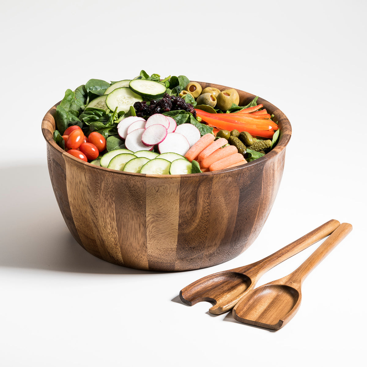 Large acacia wood salad bowl filled with fresh vegetables and paired serving utensils from DC-Kalmar Home for Home and beyond decor