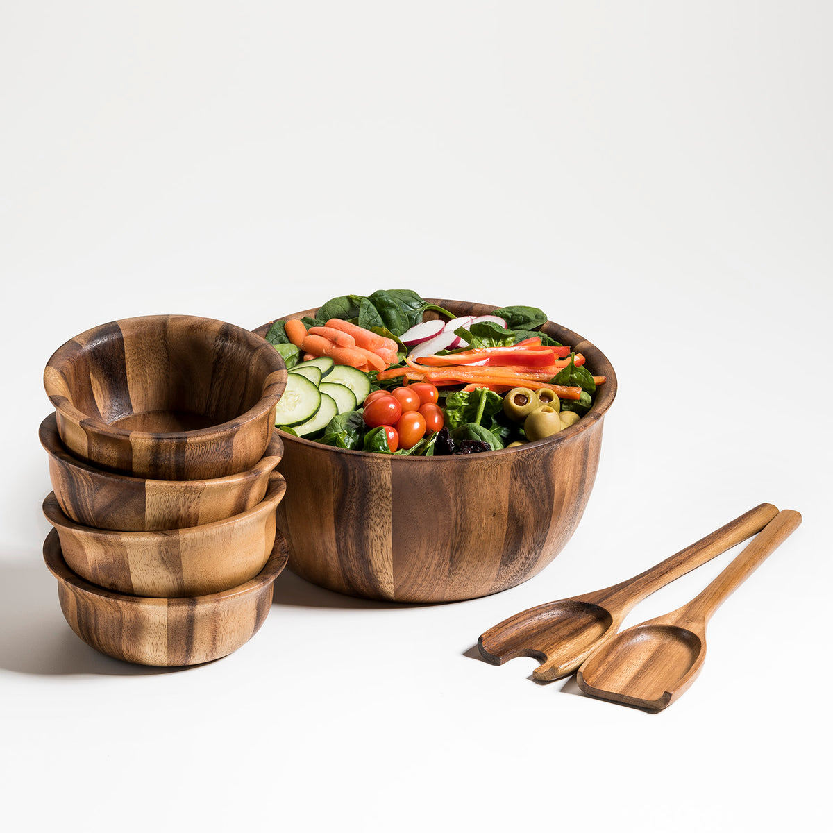 Large wooden salad bowl filled with fresh vegetables alongside four matching bowls and serving utensils from DC-Kalmar Home in Home and beyond