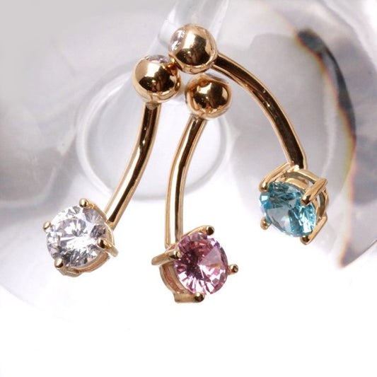 Three 14 karat yellow gold navel rings with prong set round stones in clear pink and blue displayed together by Fashion Hut Jewelry from the Jewelry collection