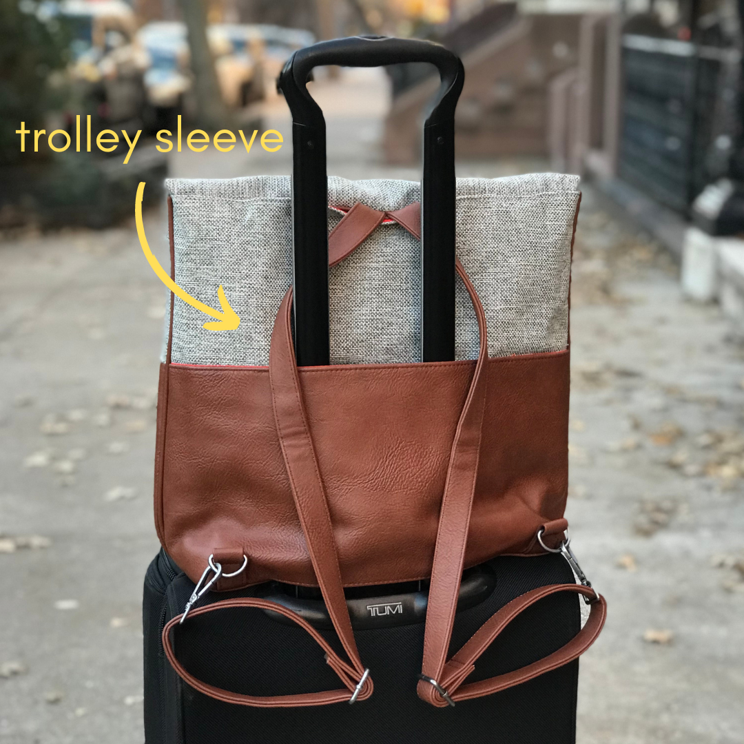 Brown and linen convertible backpack tote with a luggage sleeve sits on a rolling suitcase showing shoulder straps from DC-Canopy Verde in Bags and Belts